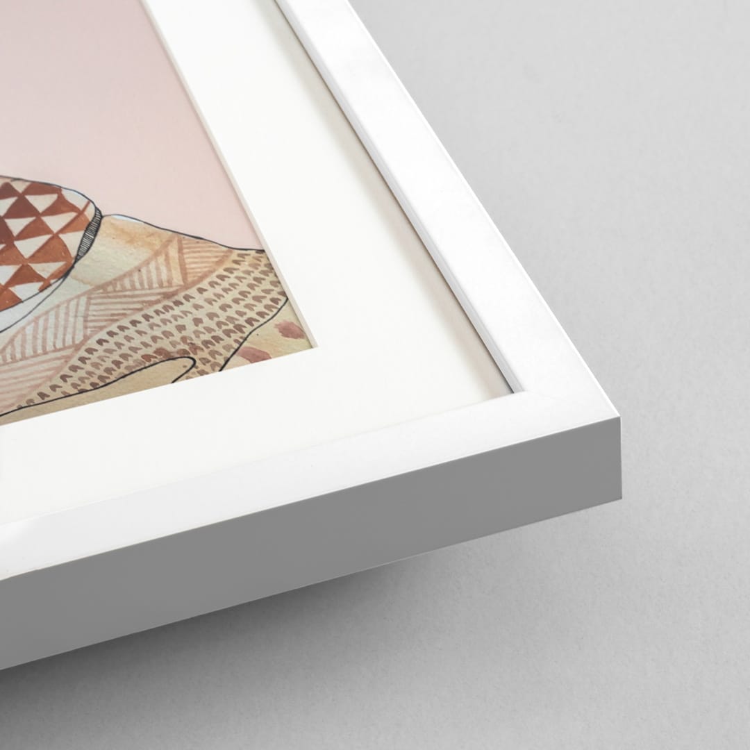 Close-up of a white picture frame with a white mat and a partially visible art print featuring beige, brown, and pink geometric patterns, set against a light gray background.