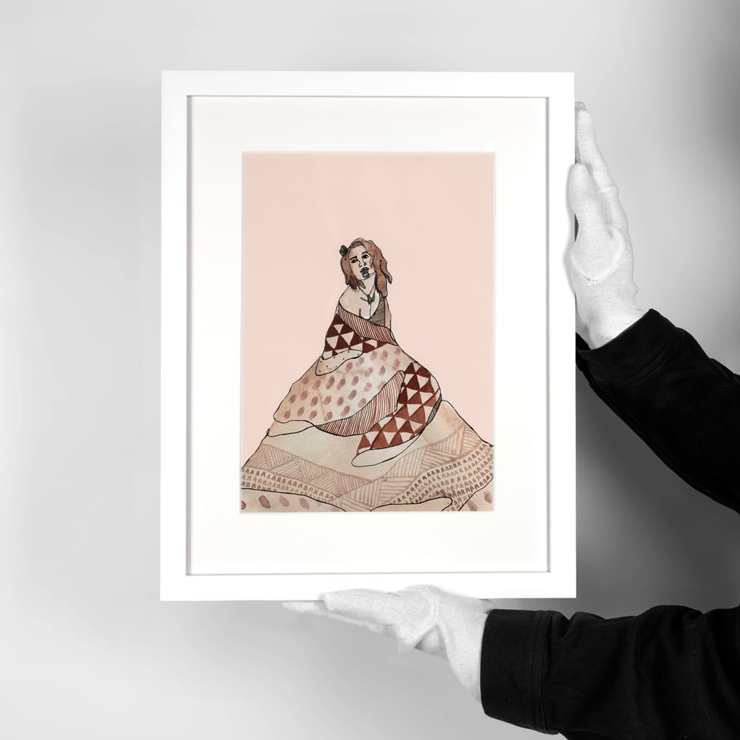 A framed art print featuring a stylized illustration of a woman in a patterned dress, held by gloved hands against a neutral gray background.